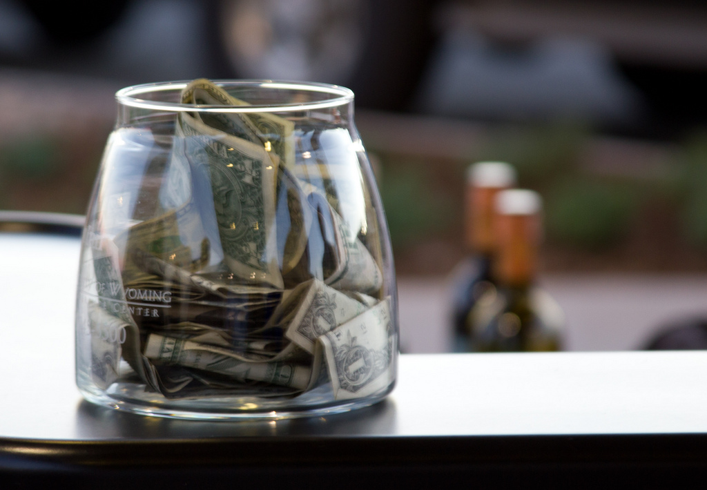 A tip jar sits on a bar counter