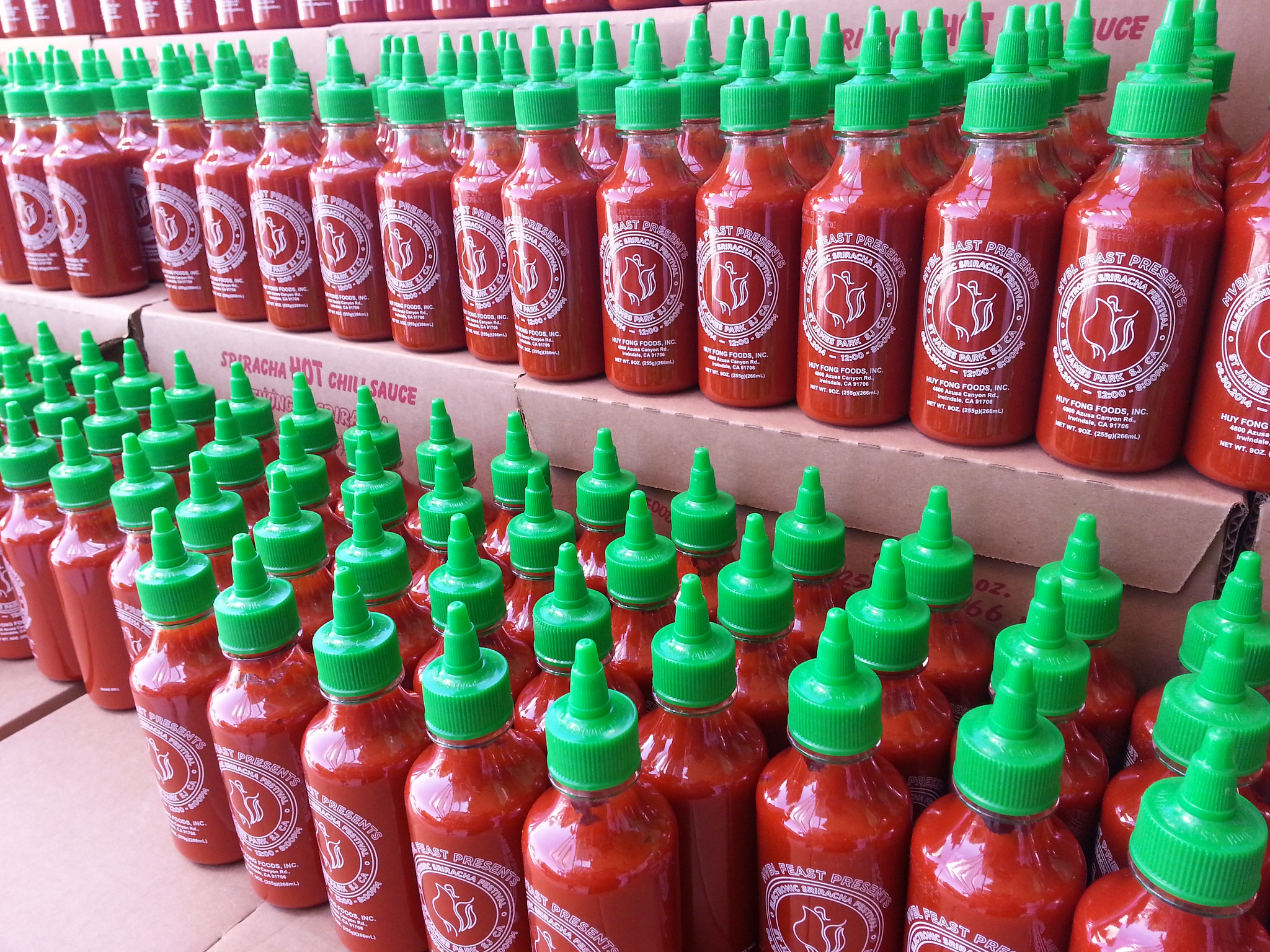 Sriracha bottles on a shelf.