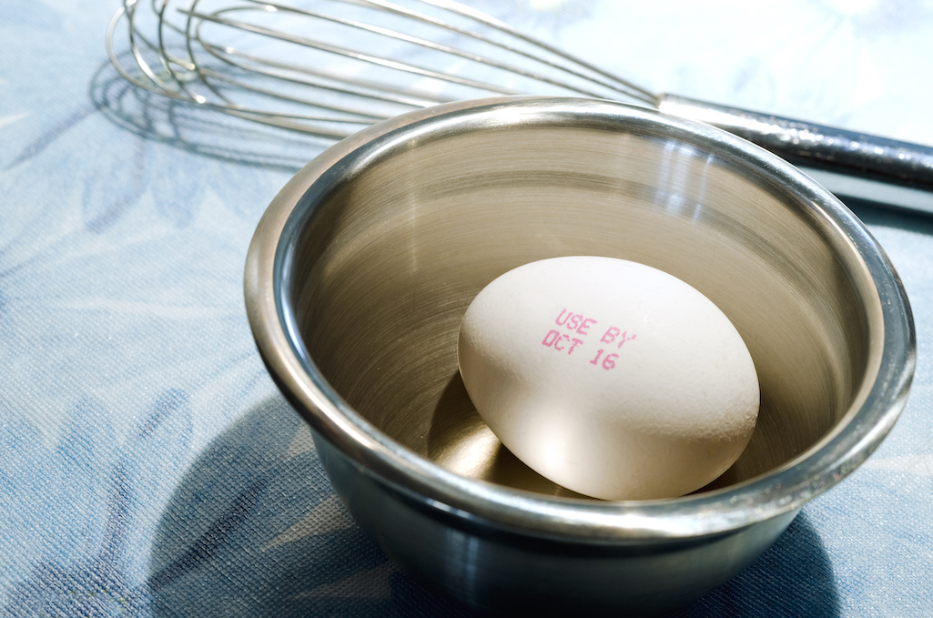 Single egg in bowl with expiration date in bowl.