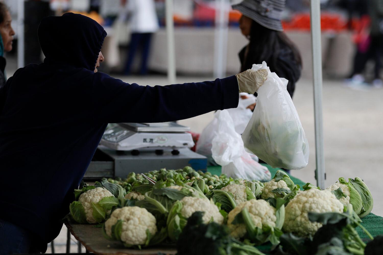 CA farmers market vendor with gloves bagging cauliflower covid-19 March 2020
