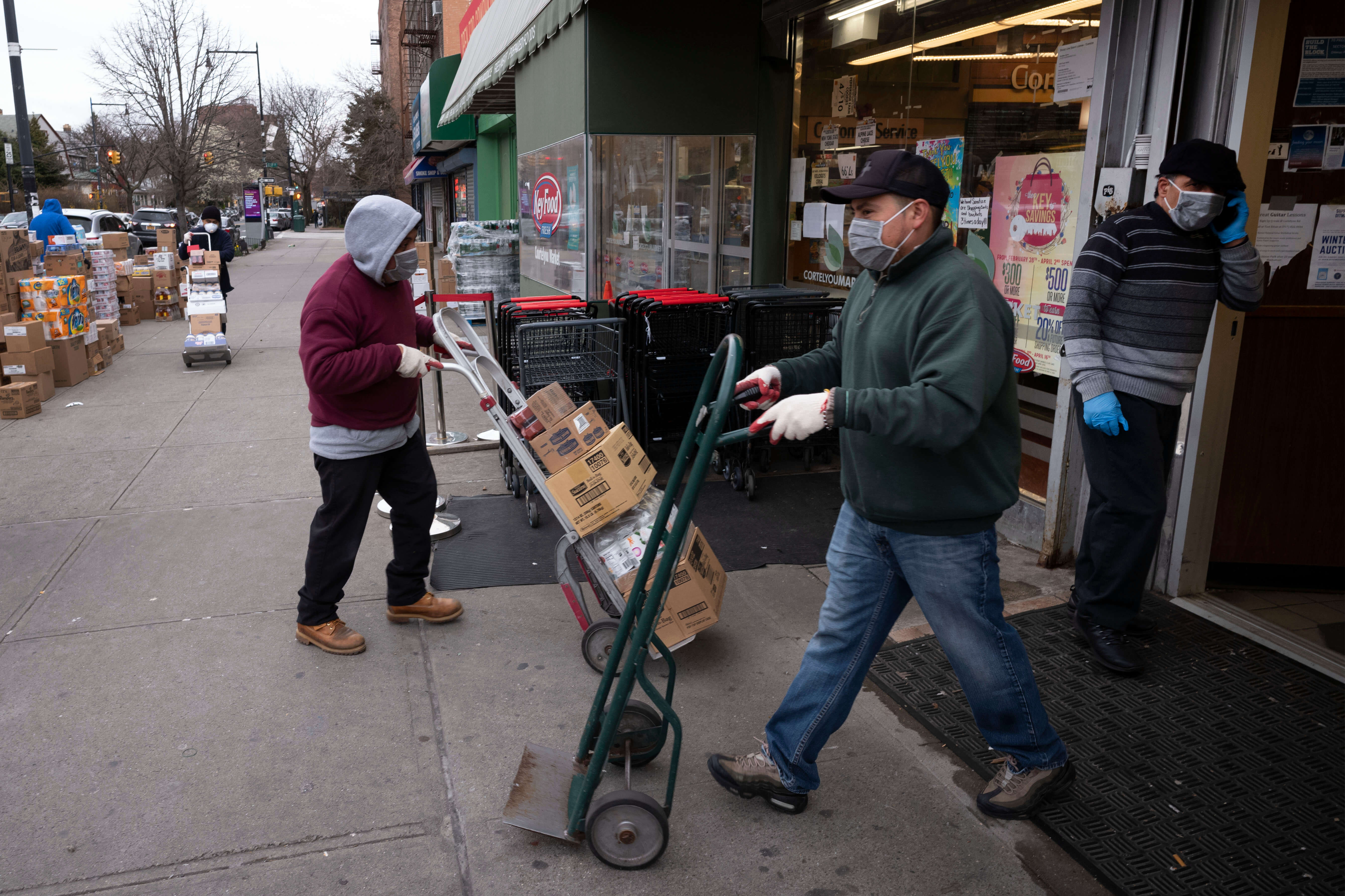 Supermarket workers wearing masks use hand carts to move food into the store during the coronavirus pandemic in the Brooklyn borough of New York. (March 2020)
