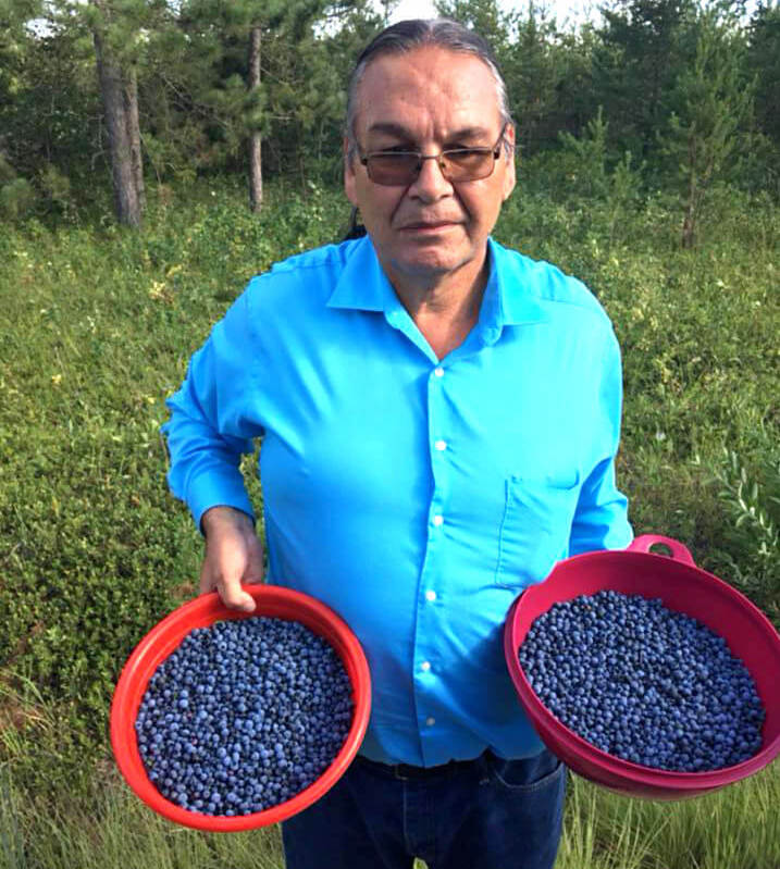 Barett's grandpa holds two bowls of blueberries picked on the Ojibwe reservation in northern Minneesota. April 2020.