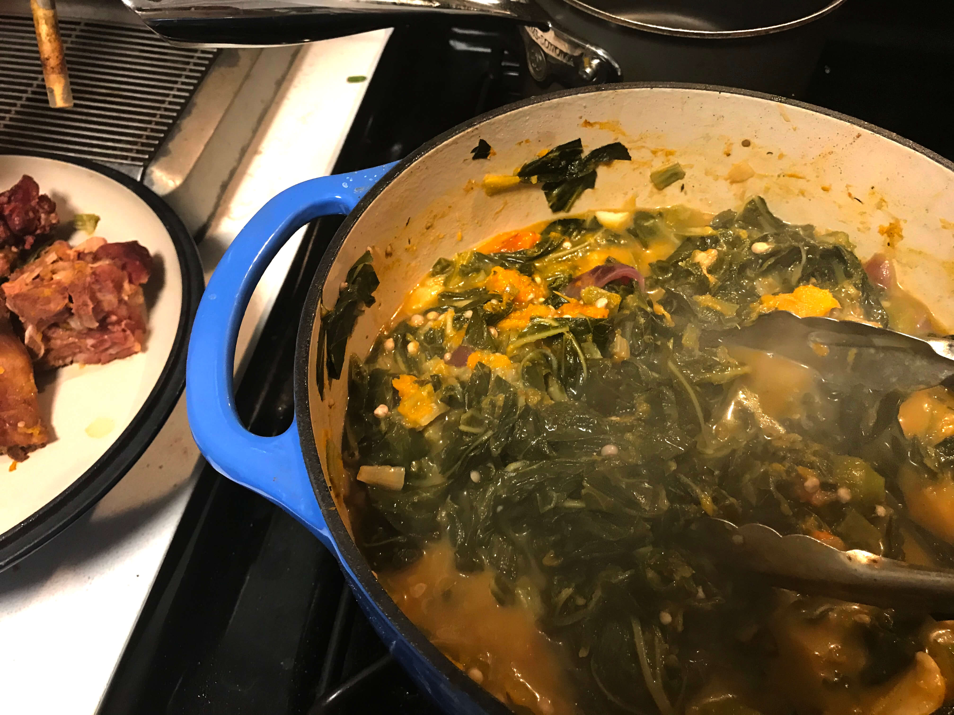 A pot of callaloo, an Afro Caribbean dish, cooks on top of a stove. An adapted American version is made with collard greens, frozen chopped okra, and butternut squash. April 2020
