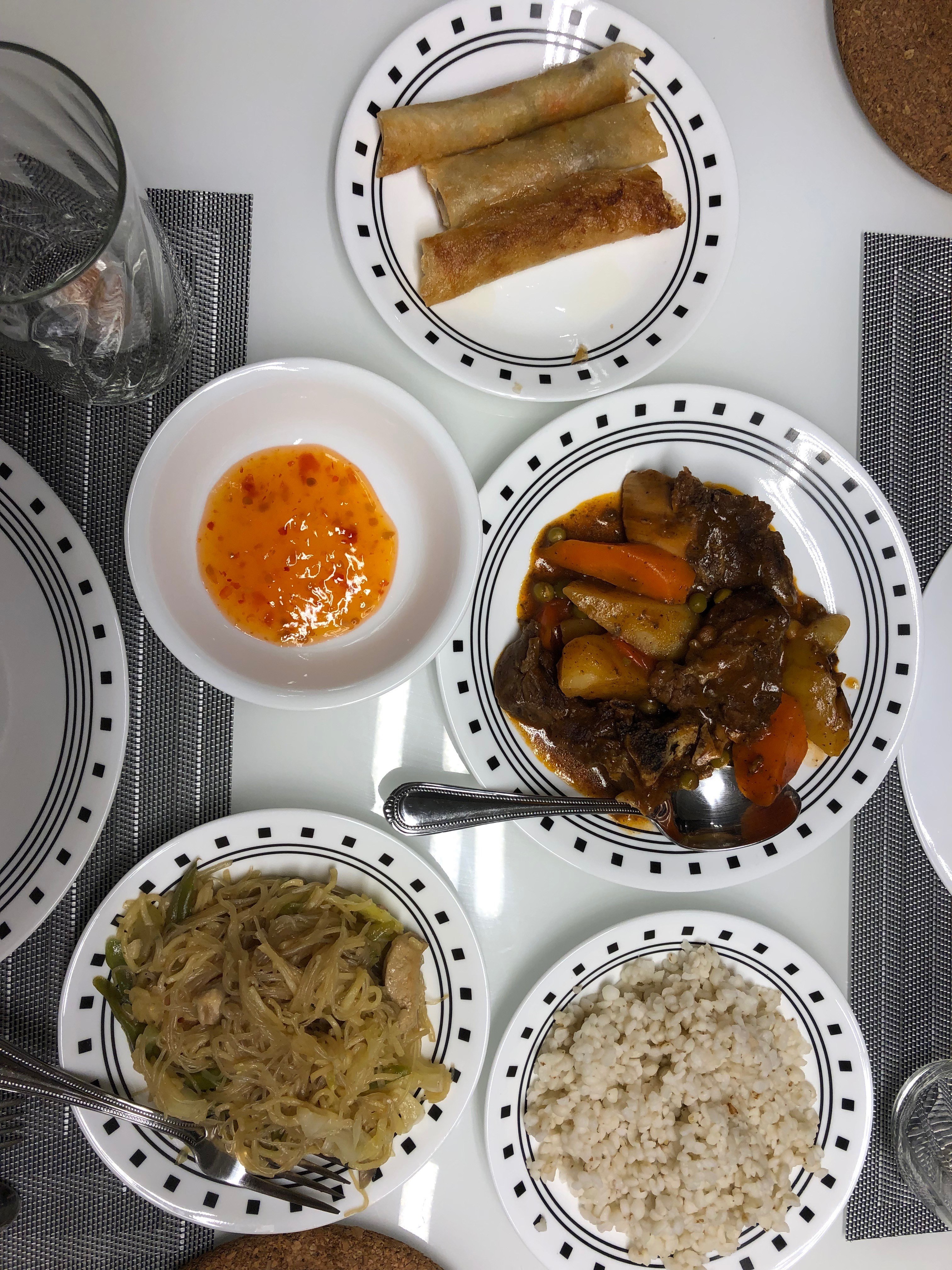 A home cooked meal Cynthia had in the Philippines: vegetable lumpia, pancit, beef afritada, jacob's tears (instead of white rice). (April 2020)