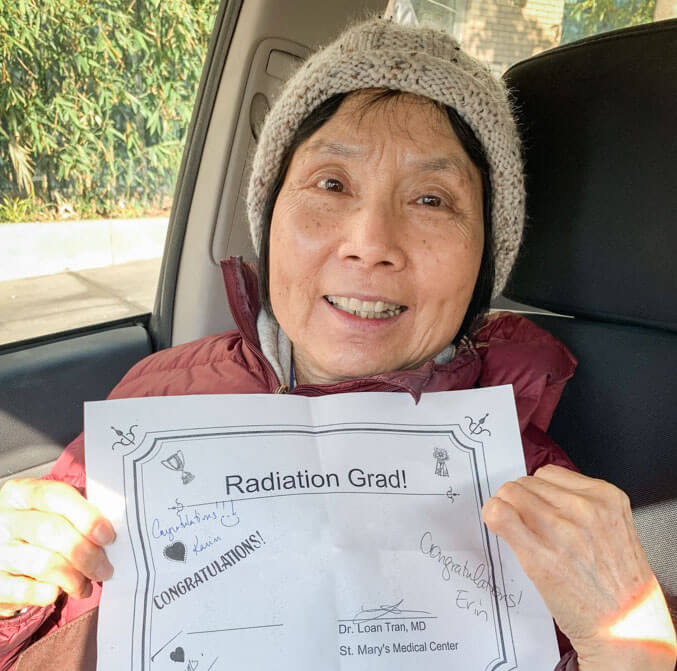 A photo the author's mom smiling and holding up a certificate that says 