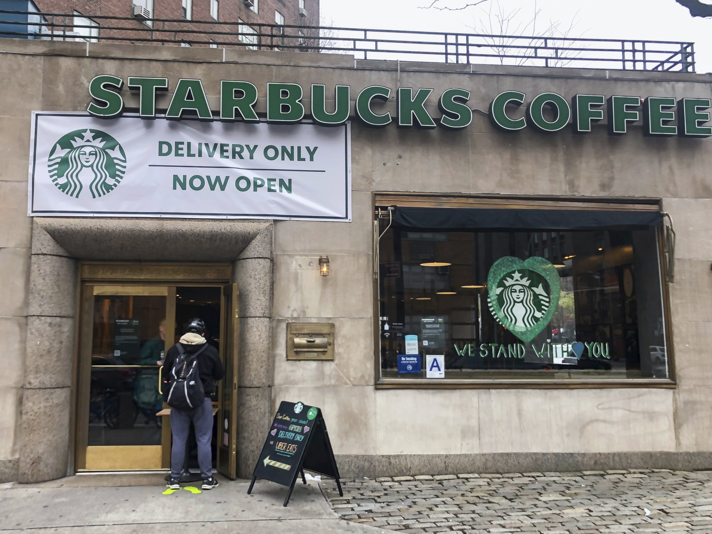 A customer waits outside for an order at Starbucks on 23rd and 1st Avenue in New York on April 8, 2020. New Yorkers continue to live under stay at home orders issued by New York Governor Andrew Cuomo in order to help stop the spread of coronavirus cases. (Photo by Samuel Rigelhaupt / Sipa USA)(Sipa via AP Images) (April 2020)