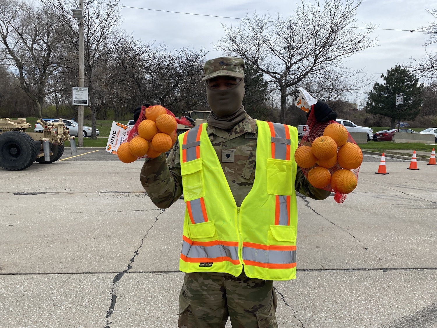 a soldier holds two bags of oranges with a full face mask on in Cleveland, Ohio, May 2020