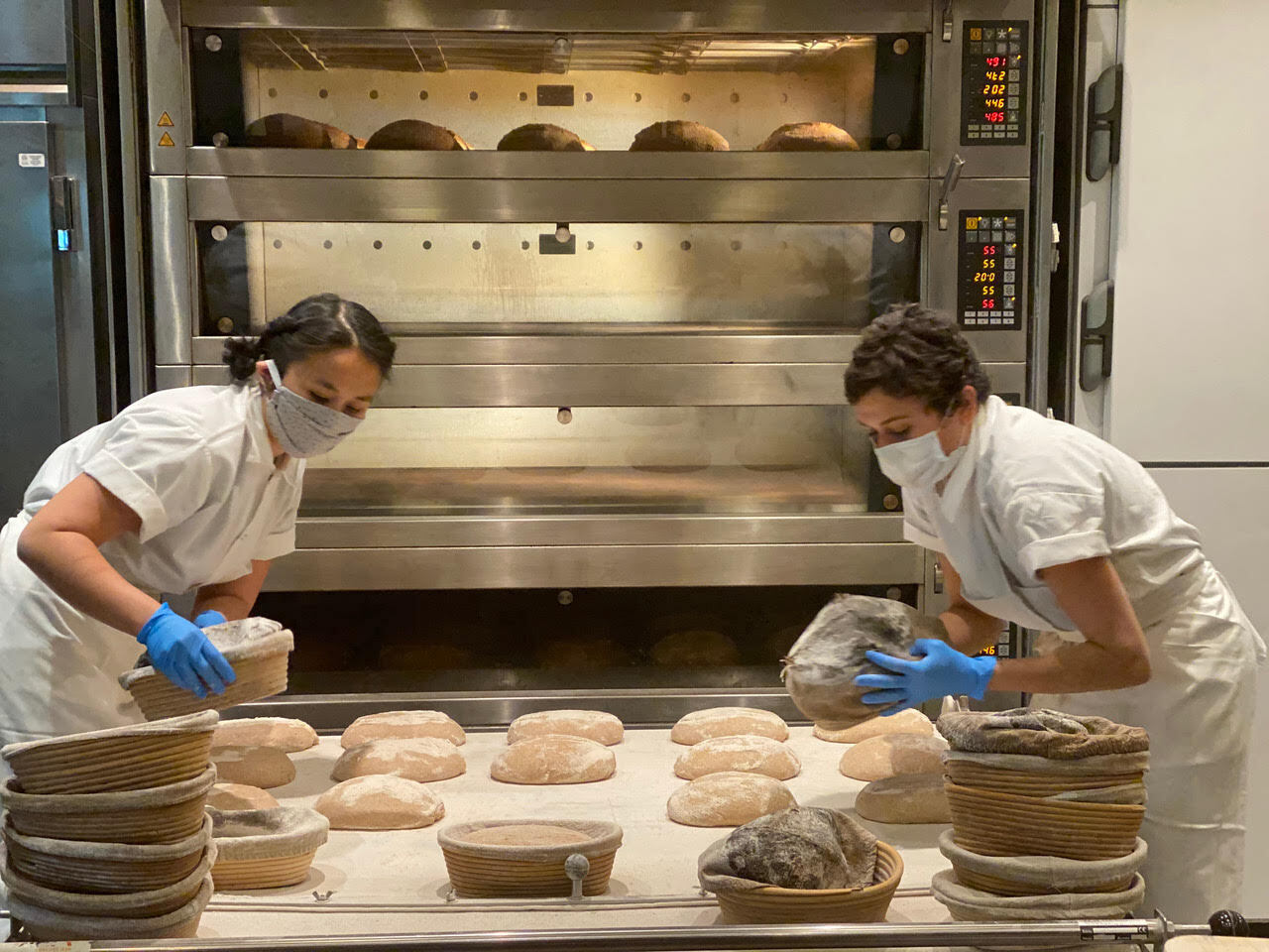 two masked and gloved bakers handle loaves of bread, Dan Barber, May 2020