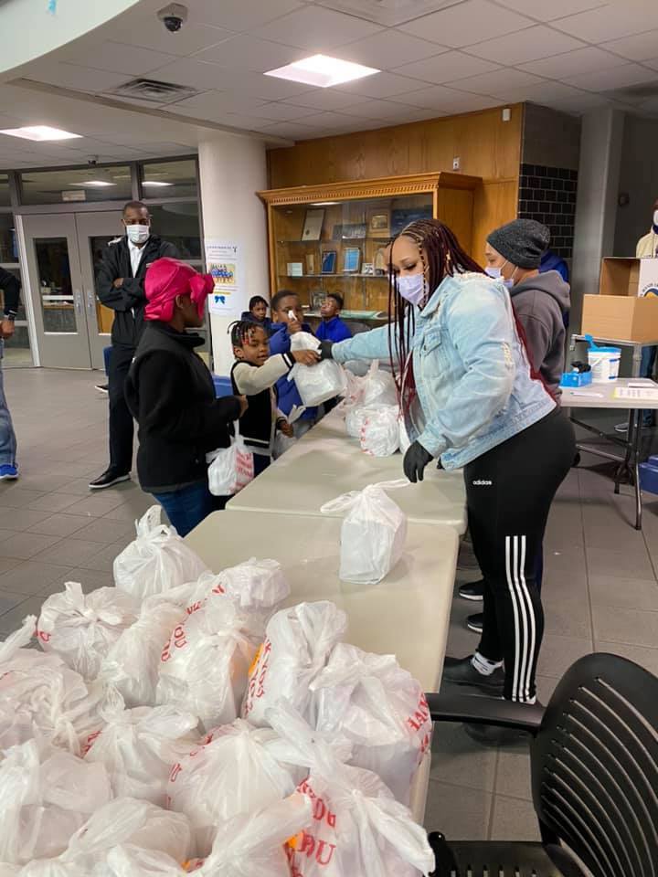 A woman passes grab-and-go meals to children at a Kansas City public school.