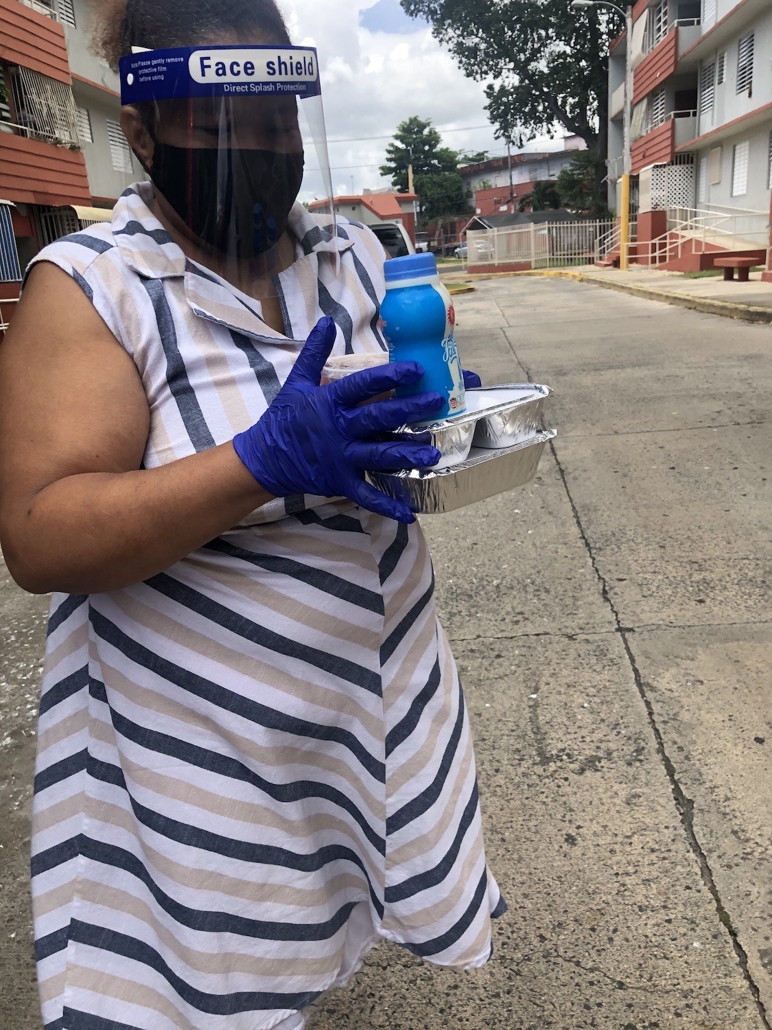 Lucia Santana distributes cooked meals provided by the municipality of San Juan, Puerto Rico, to her elderly neighbors June 2020