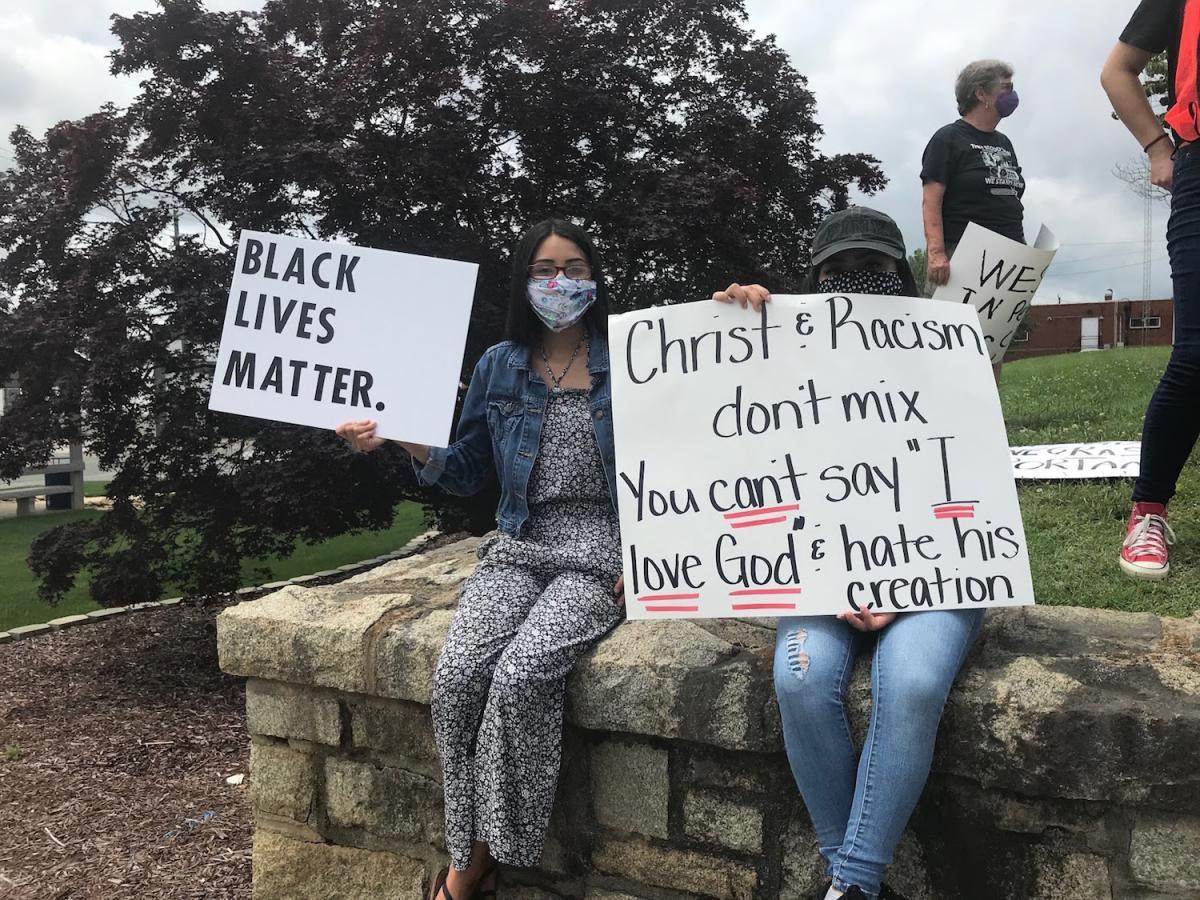 Two protesters are seated on a stone ledge holding BLM signs. June 2020