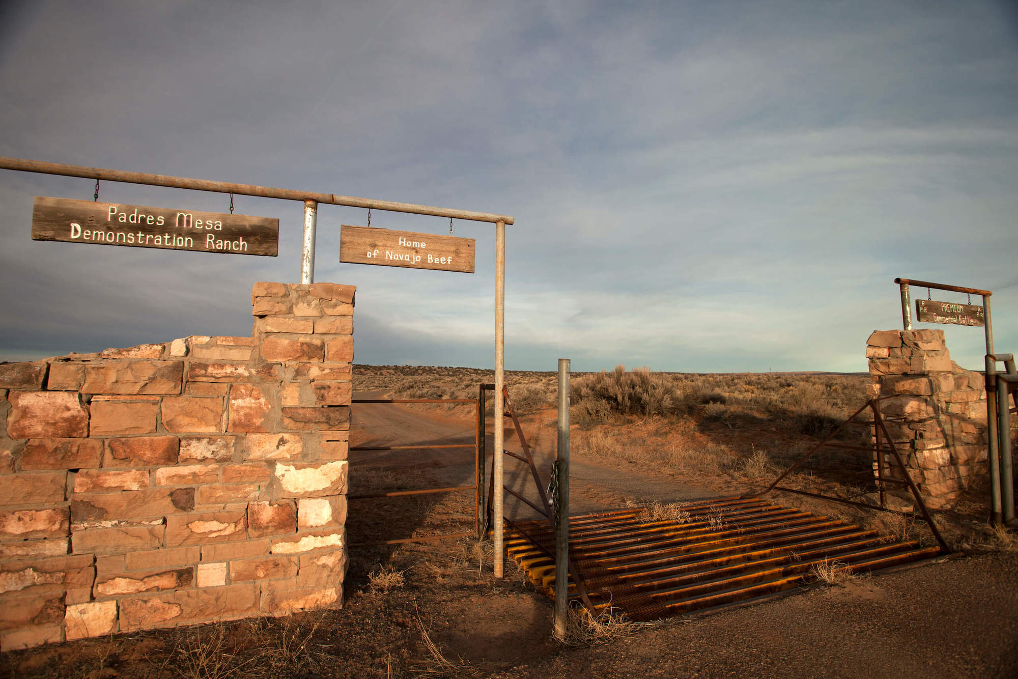 A brick wall with two signs above that read Padres Mesa Demonstration Ranch and Home of Navajo Beef. June 2020