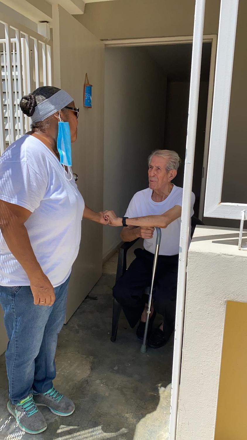 A volunteer visits one of the elderly neighbors at Manuel A. Perez Housing Project in San Juan, Puerto Rico, who receives cooked meals through the emergency food distribution June 2020