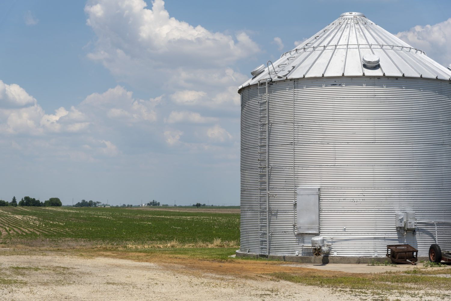 The farm of Greg St. Albin near Manteno, IL. A large silver silo sits next to an open field of tilled grass. July 2020