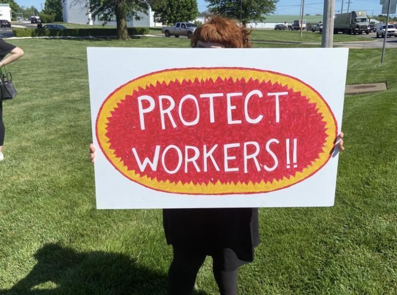 Poultry worker advocate holds up a sign that reads 