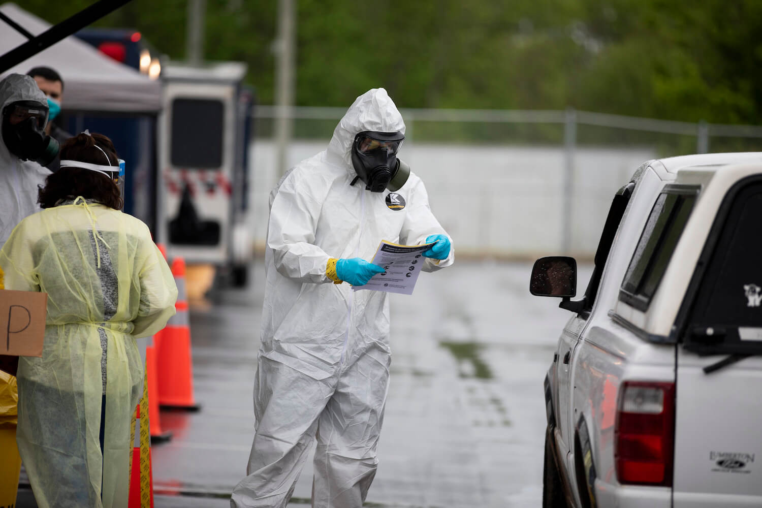 A health worker wearing a hazmat suit conducts a covid-19 test in a drive-thru testing site. August 2020