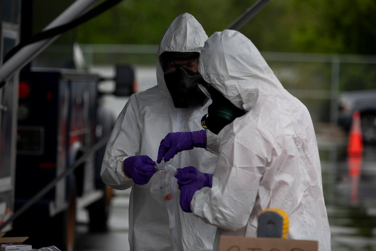 Two health officials wearing hazmat suits and gloves. August 2020