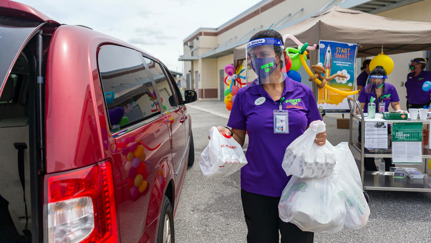Aline Martins, center, distributes free and reduced lunch during the first day of classes in Broward County at Discovery Elementary School in Sunrise, Fla., on Wednesday, Aug. 19, 2020.