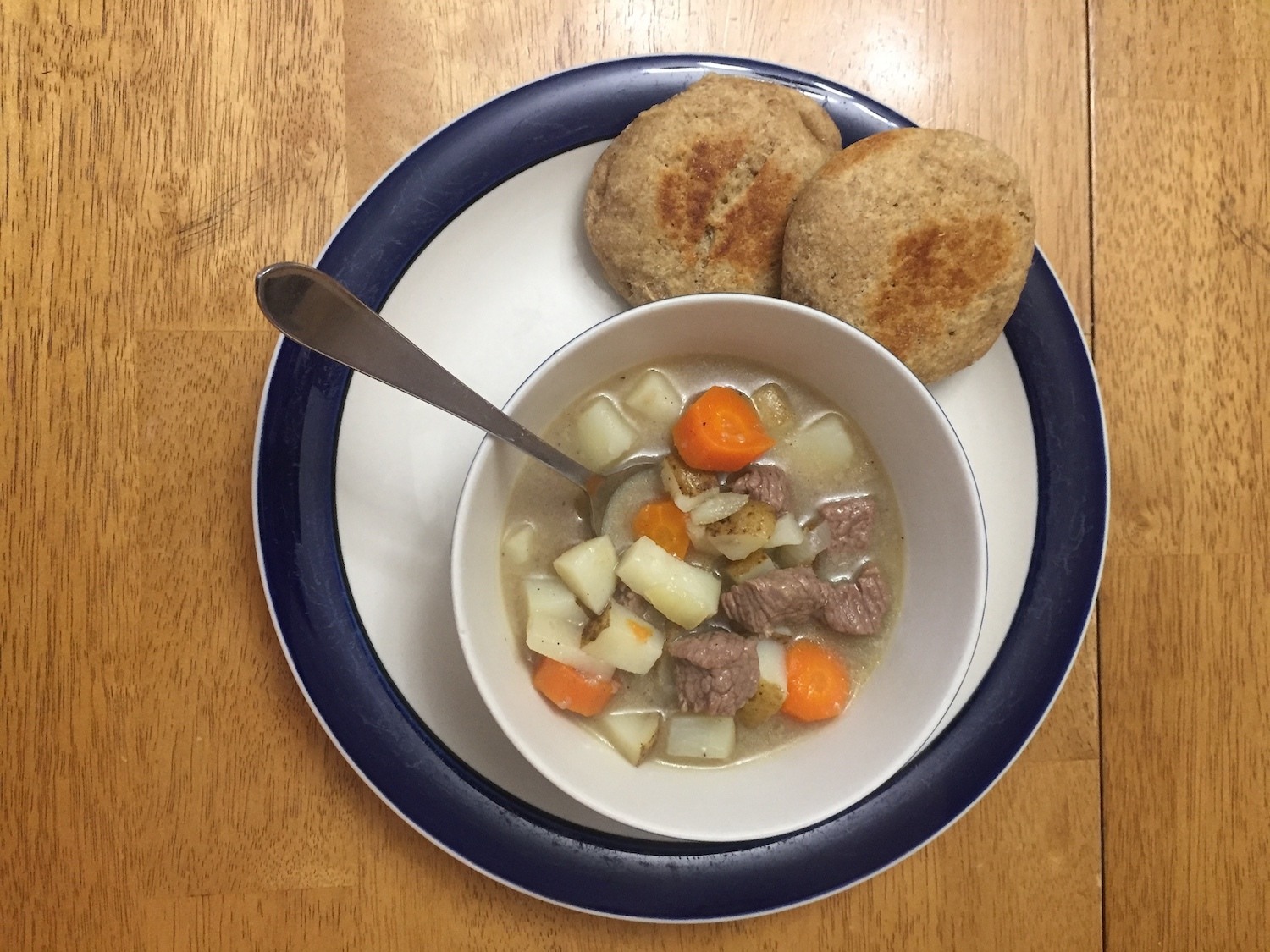 A bowl of meat stew with potatoes, carrots, and two biscuits. September 2020