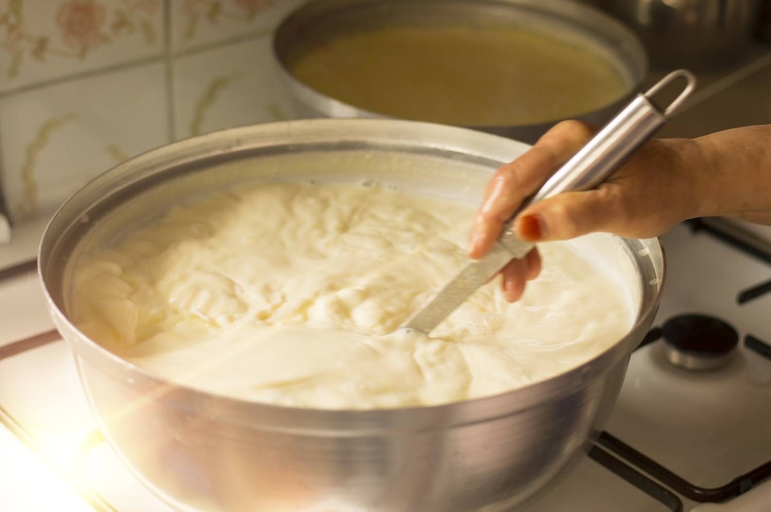A hand preparing yogurt stirring over the stove. September 2020
