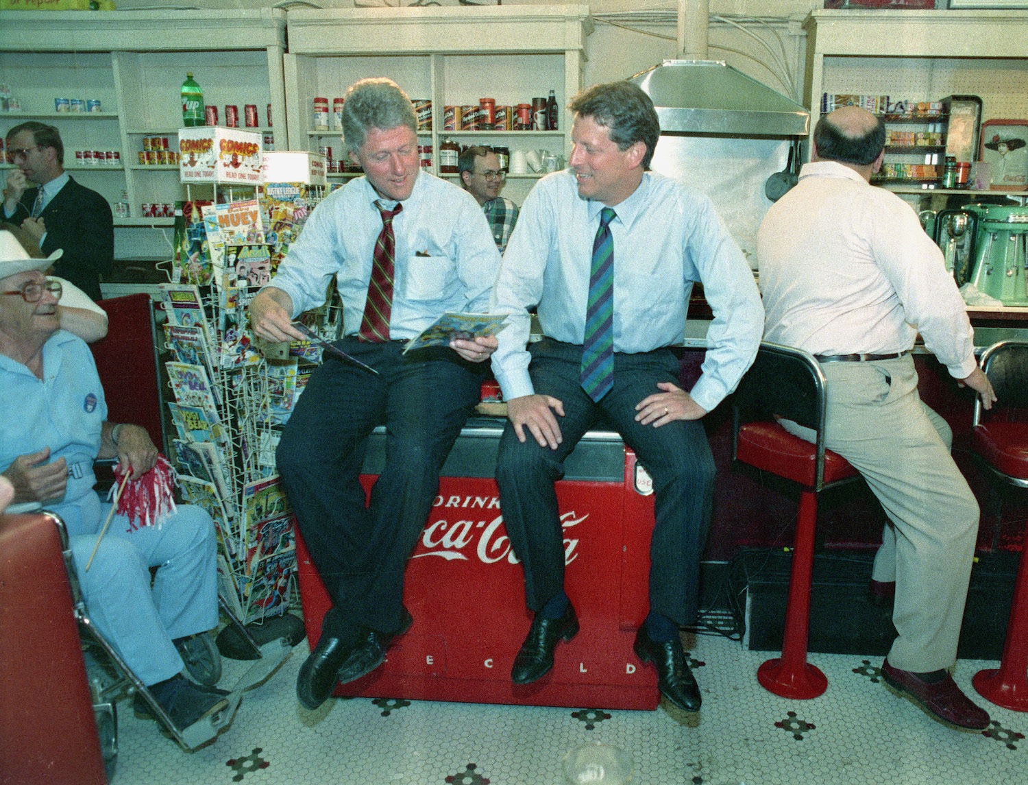 Democratic running mates Gov. Bill Clinton, left, and Sen. Al Gore sit on top of a soft drink box and look over comic books at Doe's Cafe in Corsicana, Texas, Friday, Aug. 28, 1992.