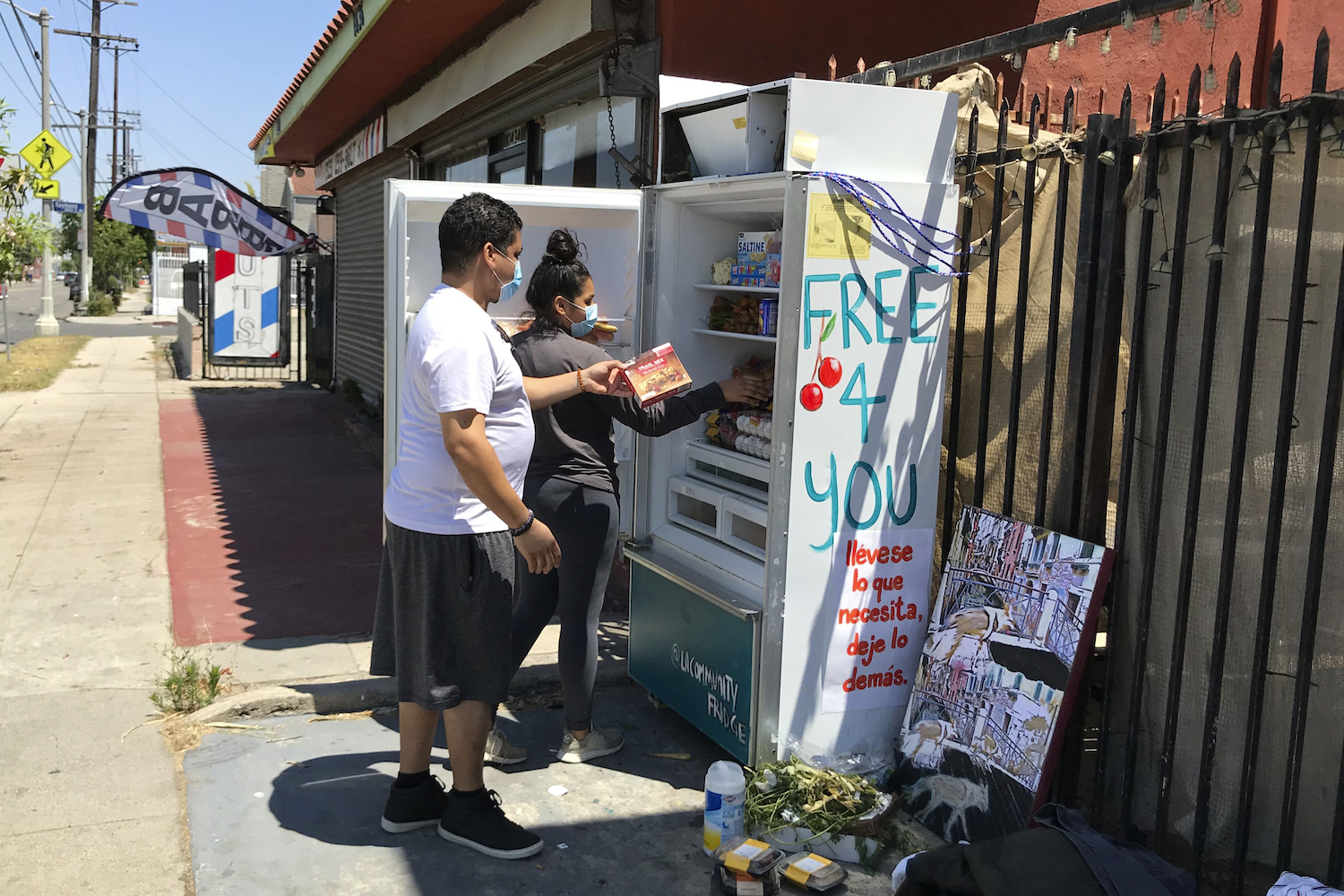 Volunteers Bryant Rodriguez and his daughter Vanessa stock a refrigerator with free food in Los Angeles. July 20, 2020.
