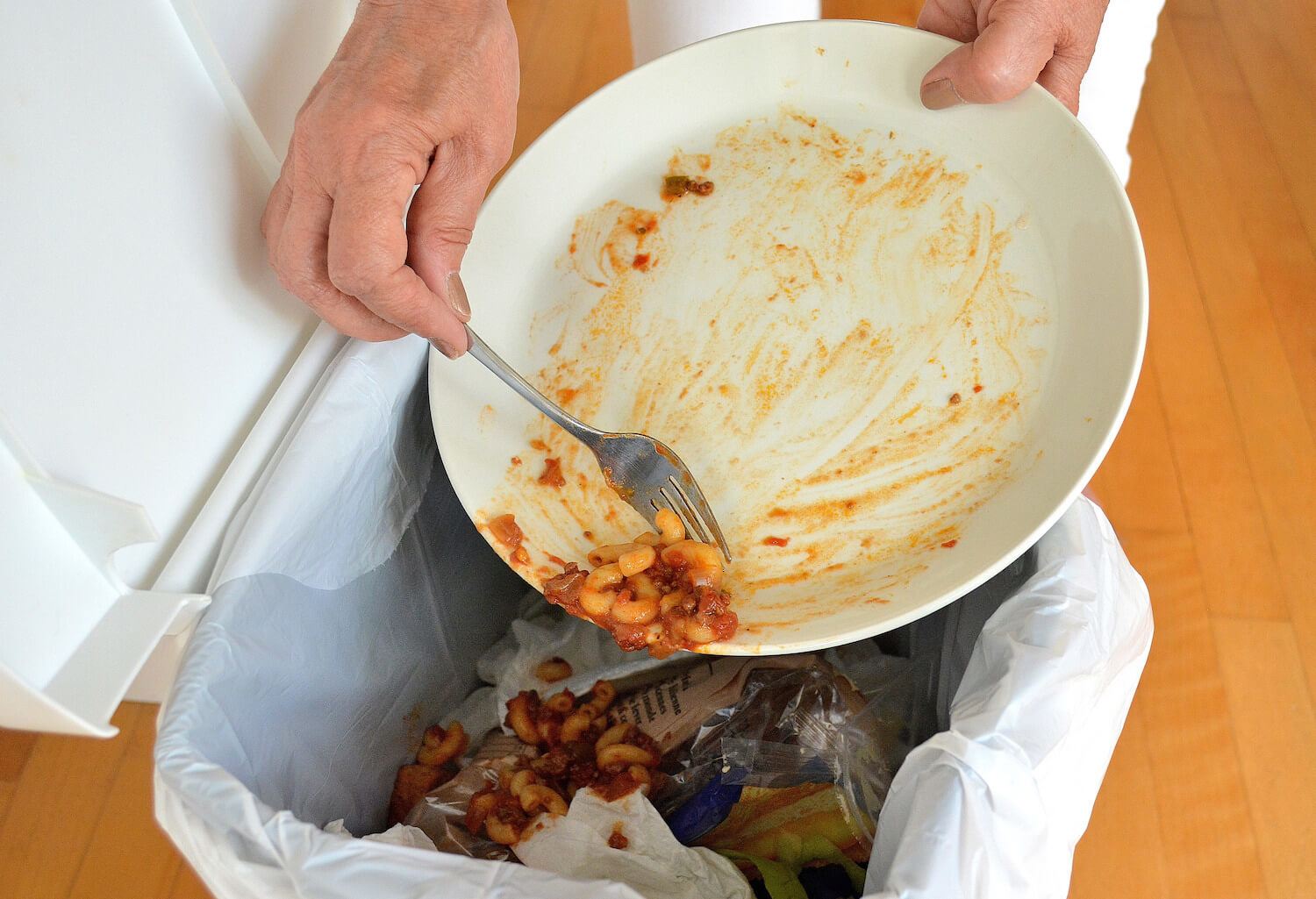 Someone scraping off food leftovers into a trash can. October 2020