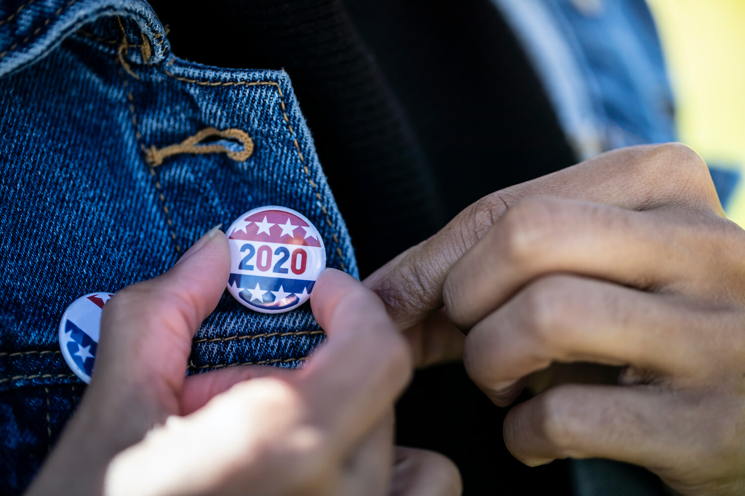 Woman holds 2020 pin to her jacket. October 2020