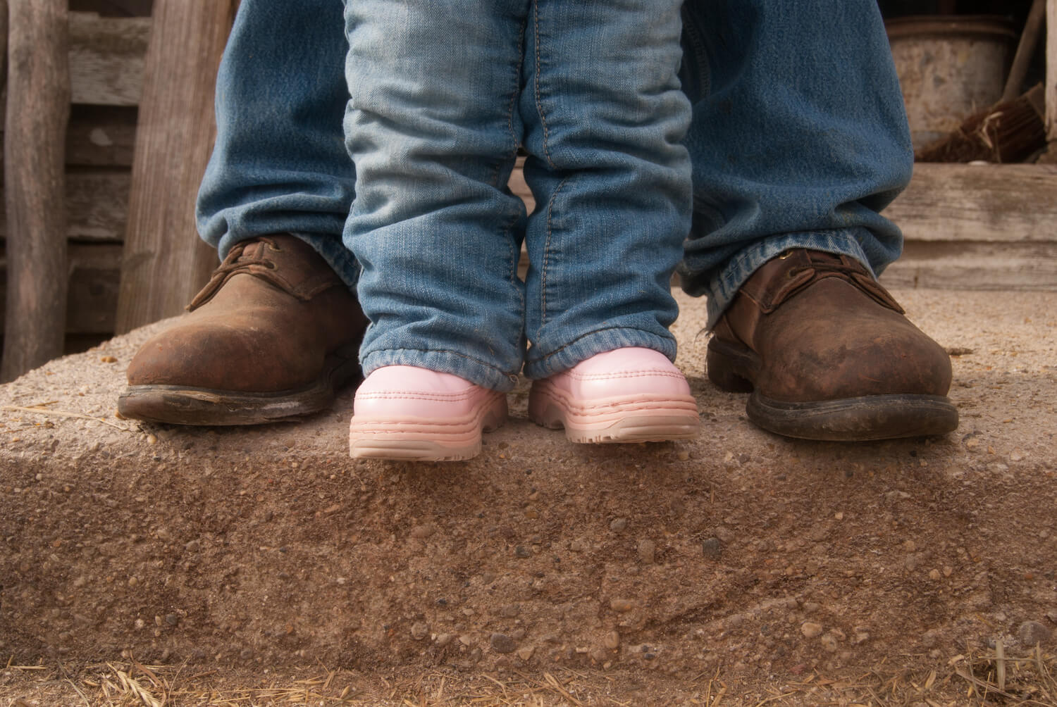A pair of pink children's boots stands next to adult boots. November 2020