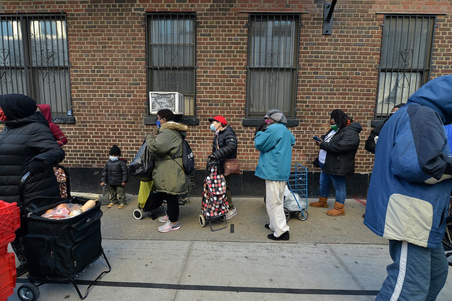 People stand in line outside the Common Pantry as they wait for NY Gov. Andrew Cuomo to distribute Thanksgiving turkeys, in New York, NY, November 24, 2020.