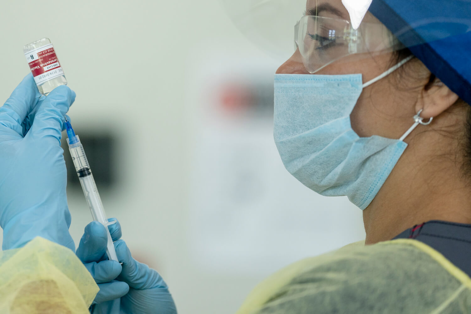 Nurse with a mask administers a Covid-19 vaccination. December 2020