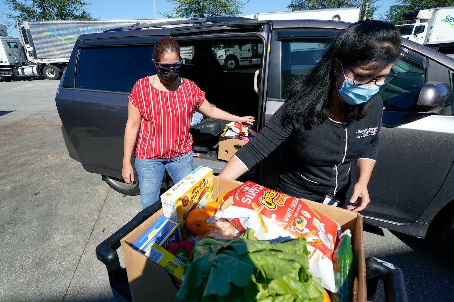Johnna Nieves, left, opens her van as Idalia Nunez, right, of the Second Harvest Food Bank loads the vehicle with a weeks supply of food in Orlando, Fla., on Tuesday, Nov. 17, 2020. While food banks have become critical during the pandemic, they're just one path for combating hunger. For every meal from a food bank, a federal program called Supplemental Nutrition Assistance Program, or food stamps _ provides nine. December 2020