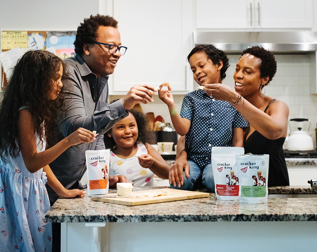 Jovani, his wife Lesley, and their three children smile while sharing samples of their cracker brand, The Cracker King in the kitchen. January 2021