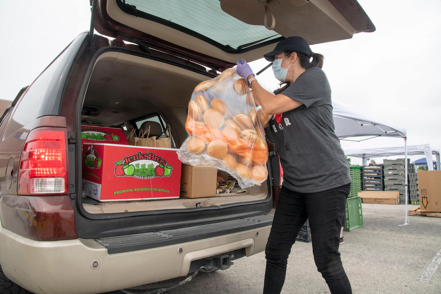 A woman loads a bag of bread distributed from a food bank during Covid. January 2021