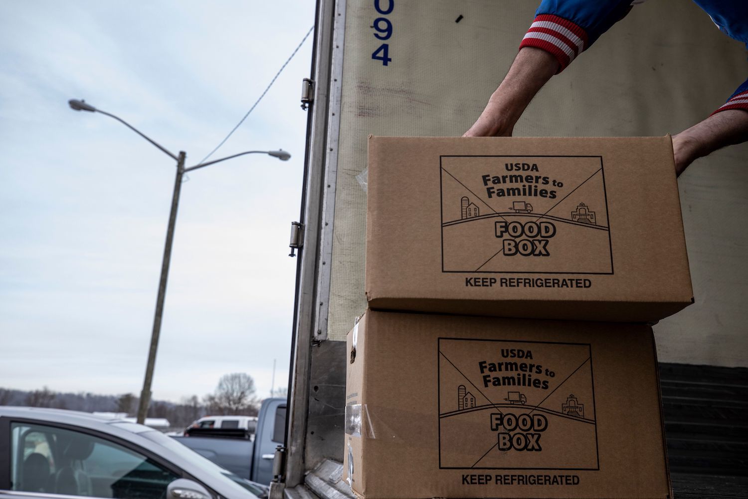 Volunteer stacks USDA Farmers to Families Food Boxes to the edge of a semi truck for distribution at the Athens County Fairgrounds in Athens, Ohio on December 19, 2020.