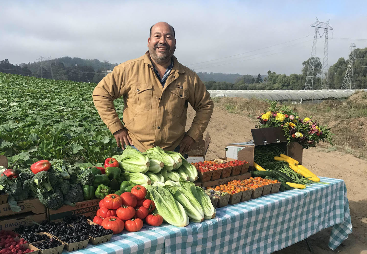 Javier Zamora stands in front of a table with his crops. March 2021