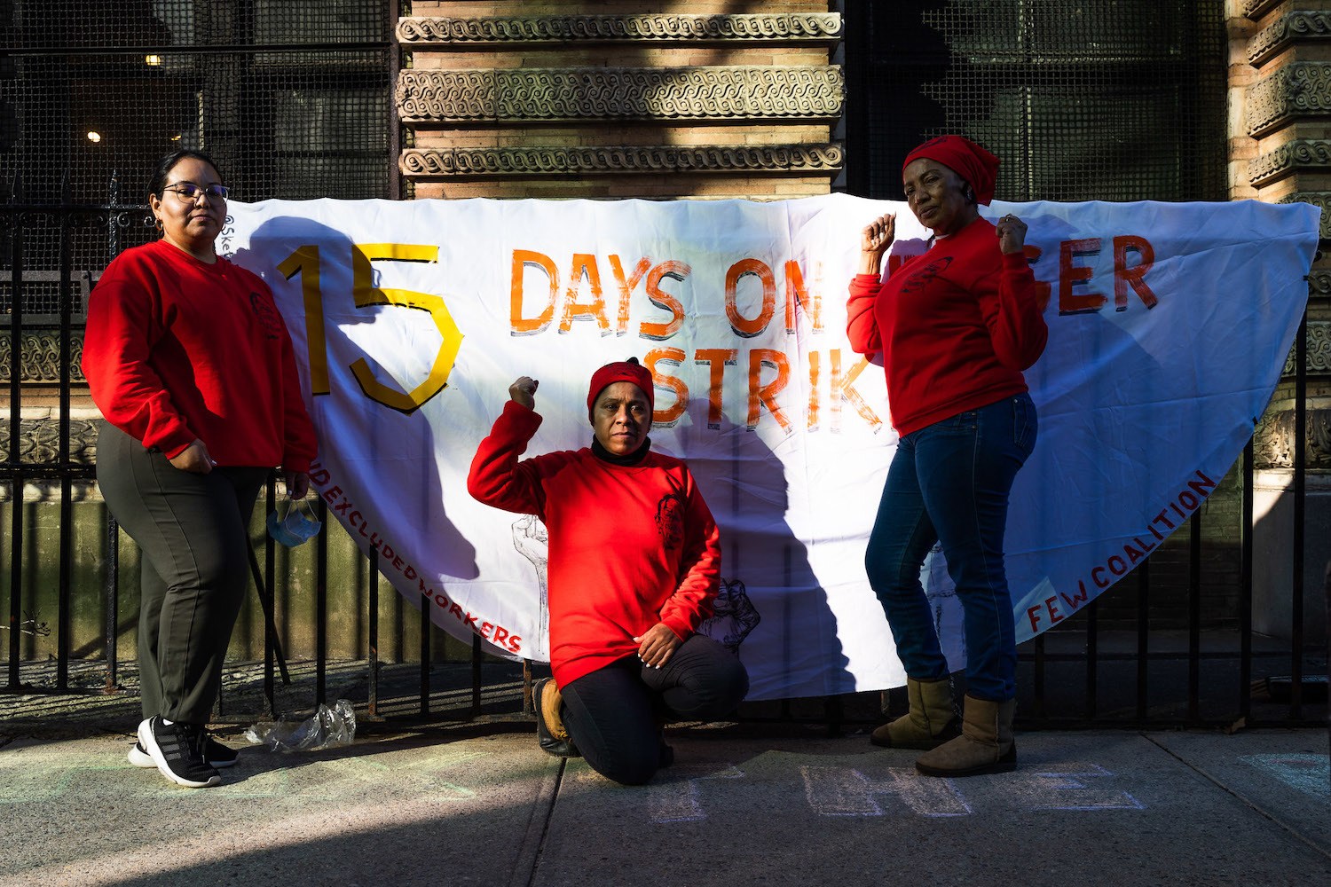 From left: Veronica Leal, Maria Isabel Sierra Mosso and Santa Arias pose in front of a sign on Thompson Street in Manhattan during a hunger strike for excluded workers. March 2021