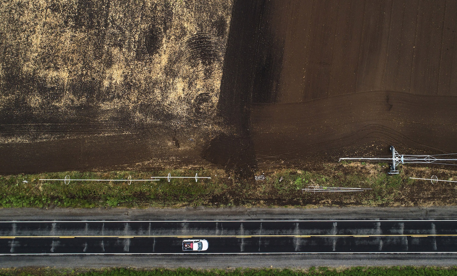 A car drives by a field owned by Walker Farms which they decided to not plant crops and left half-plowed when they learned they might lose precious water in the Klamath Basin outside Malin, Ore., on Monday, May 18, 2020.