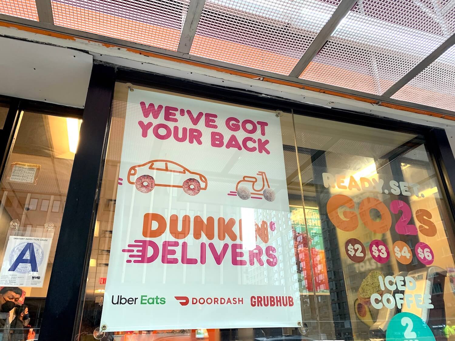 A sign outside a Dunkin Donuts window that says 