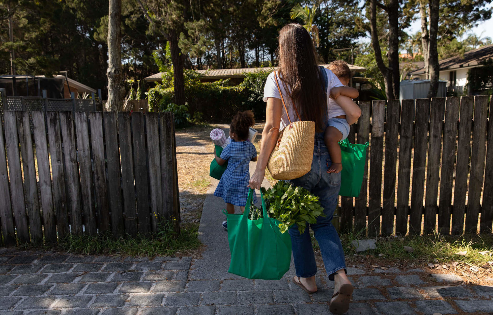 A woman and two kids carry bags of groceries. April 2021
