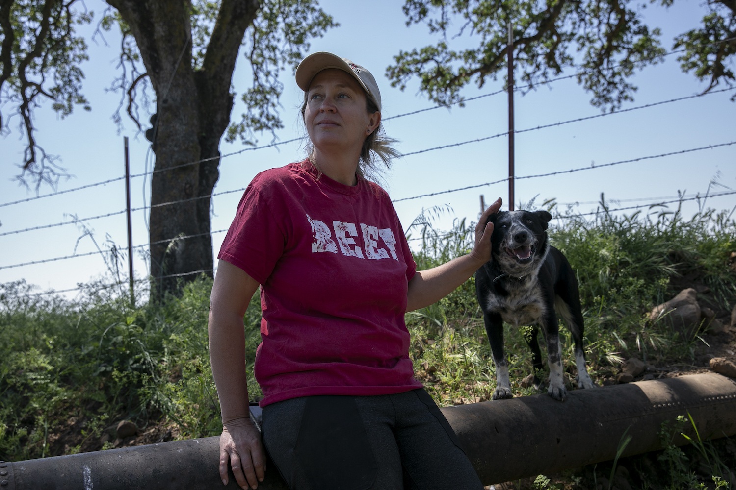 Rancher Megan Brown sits with one of her dogs in the dry creek on her property on April 22, 2021. May 2021