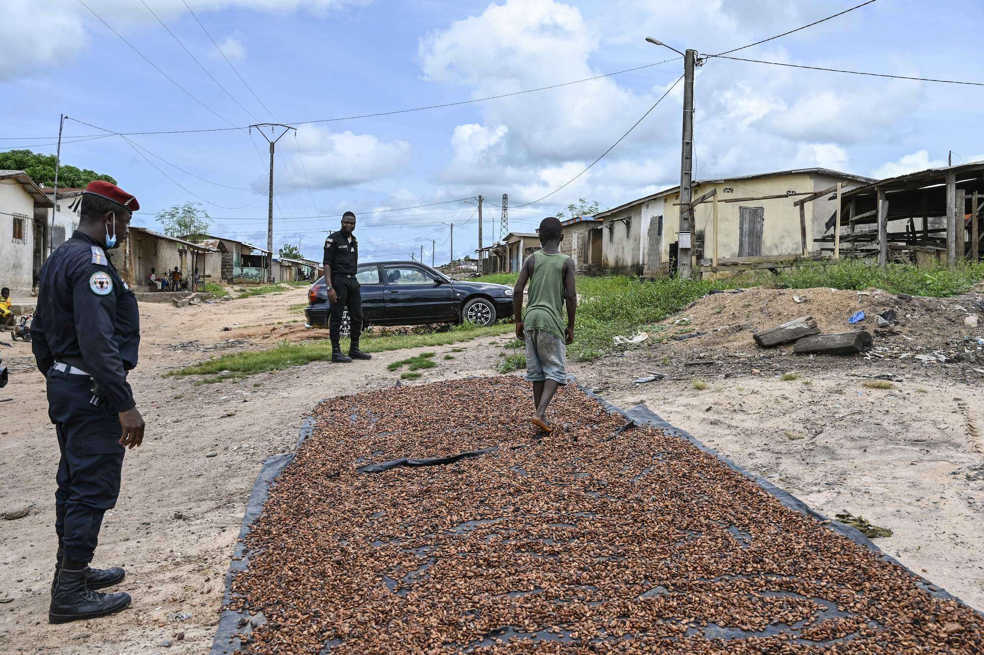 Two Ivorian gendarmes walk towards a child caught drying cocoa in the sun in the village of Opouyo in Soubre, on May 7, 2021 during an operation to remove children working on cocoa plantations. June 2021