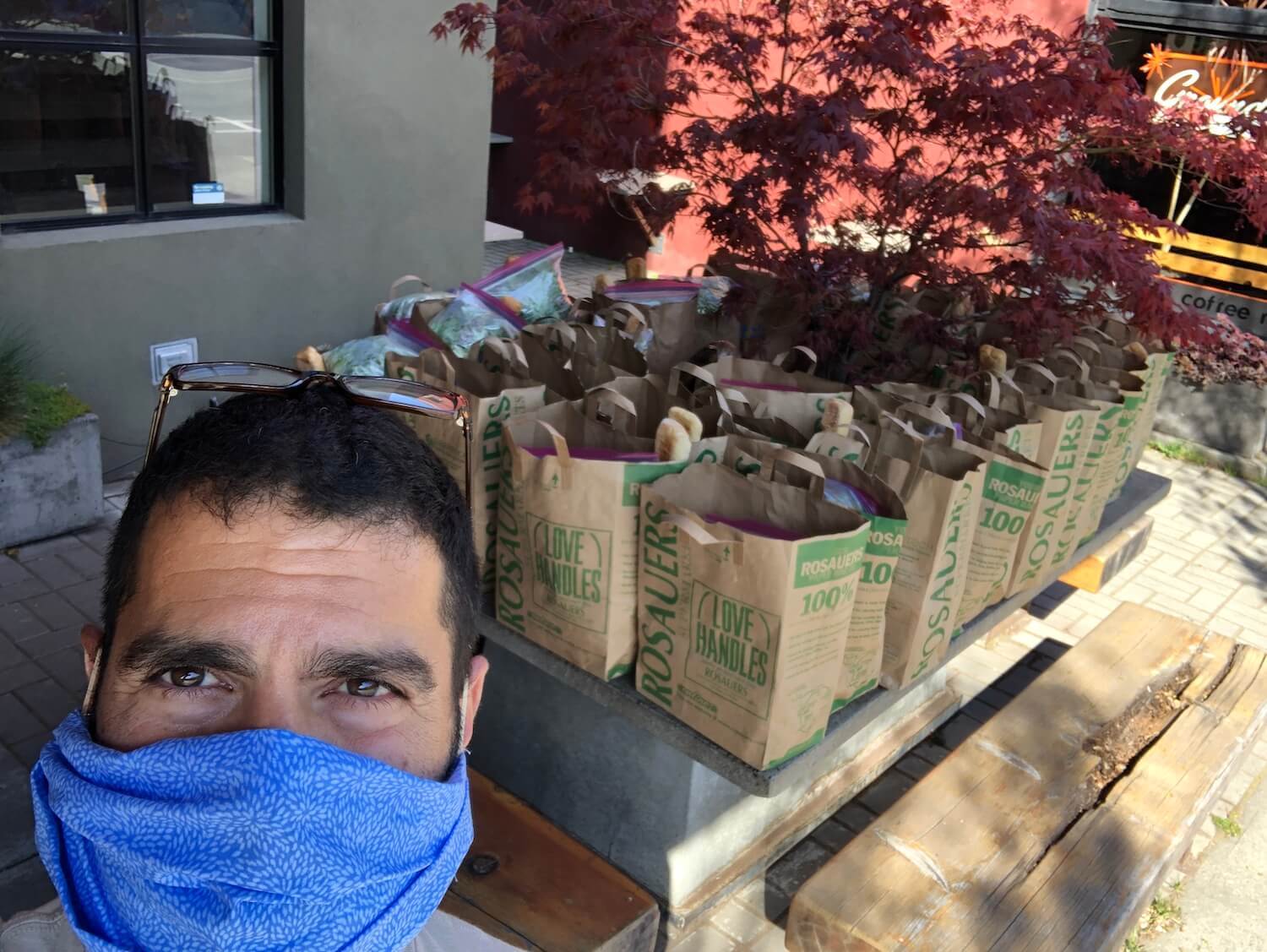 Ben Stenn takes a selfie in front of takeout meal bags. July 2021