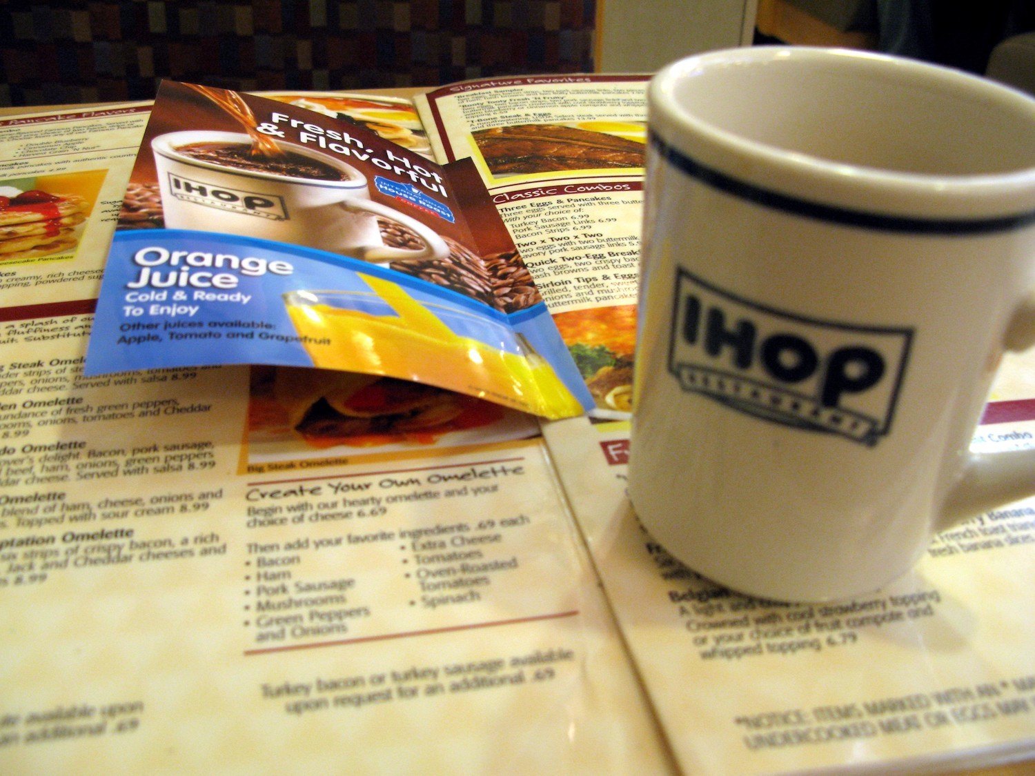 An open multi-page IHOP menu with a coffee mug on the right.