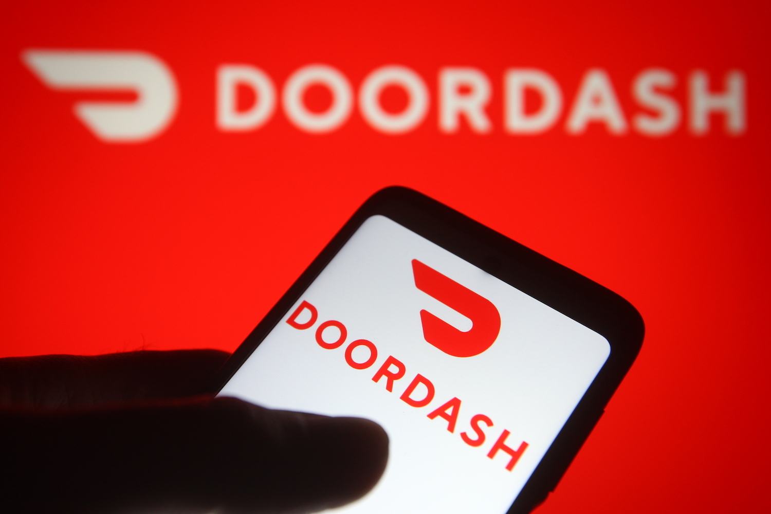In this photo illustration the DoorDash logo of an US online food ordering company is seen on a smartphone and a pc screen.
