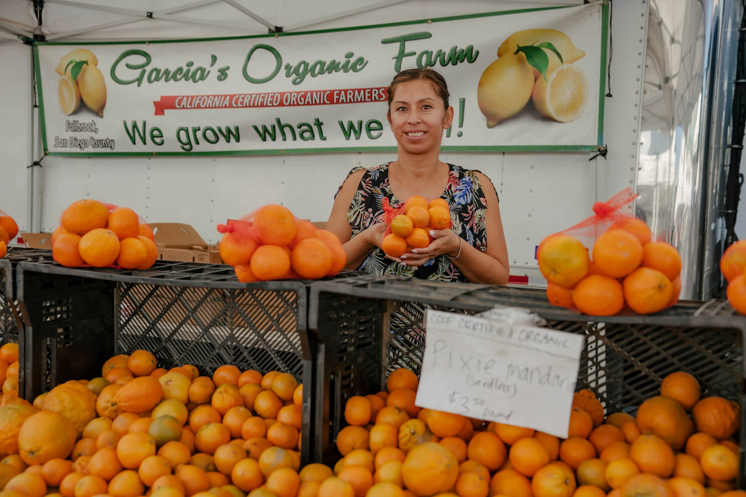 Leticia Garcia stands with Pixie mandarins at their farm stand. August 2021