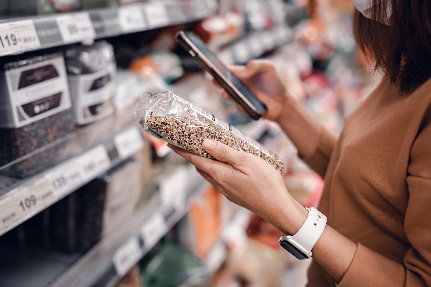 Closeup - Woman shopping in supermarket and reading product information. Costumer buying food at the market. August 2021