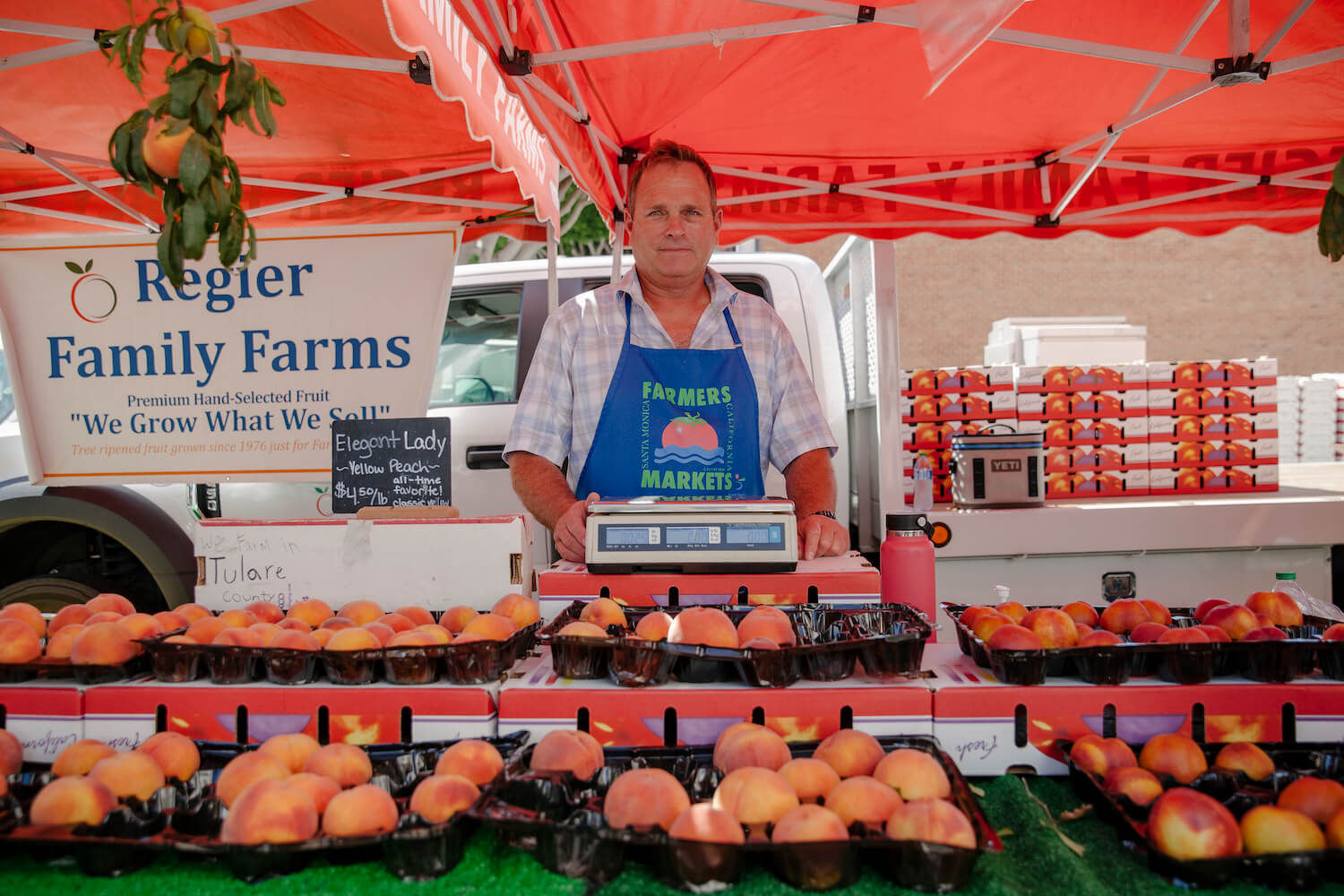 Troy Regier stands with farm stand of stone fruit. August 2021