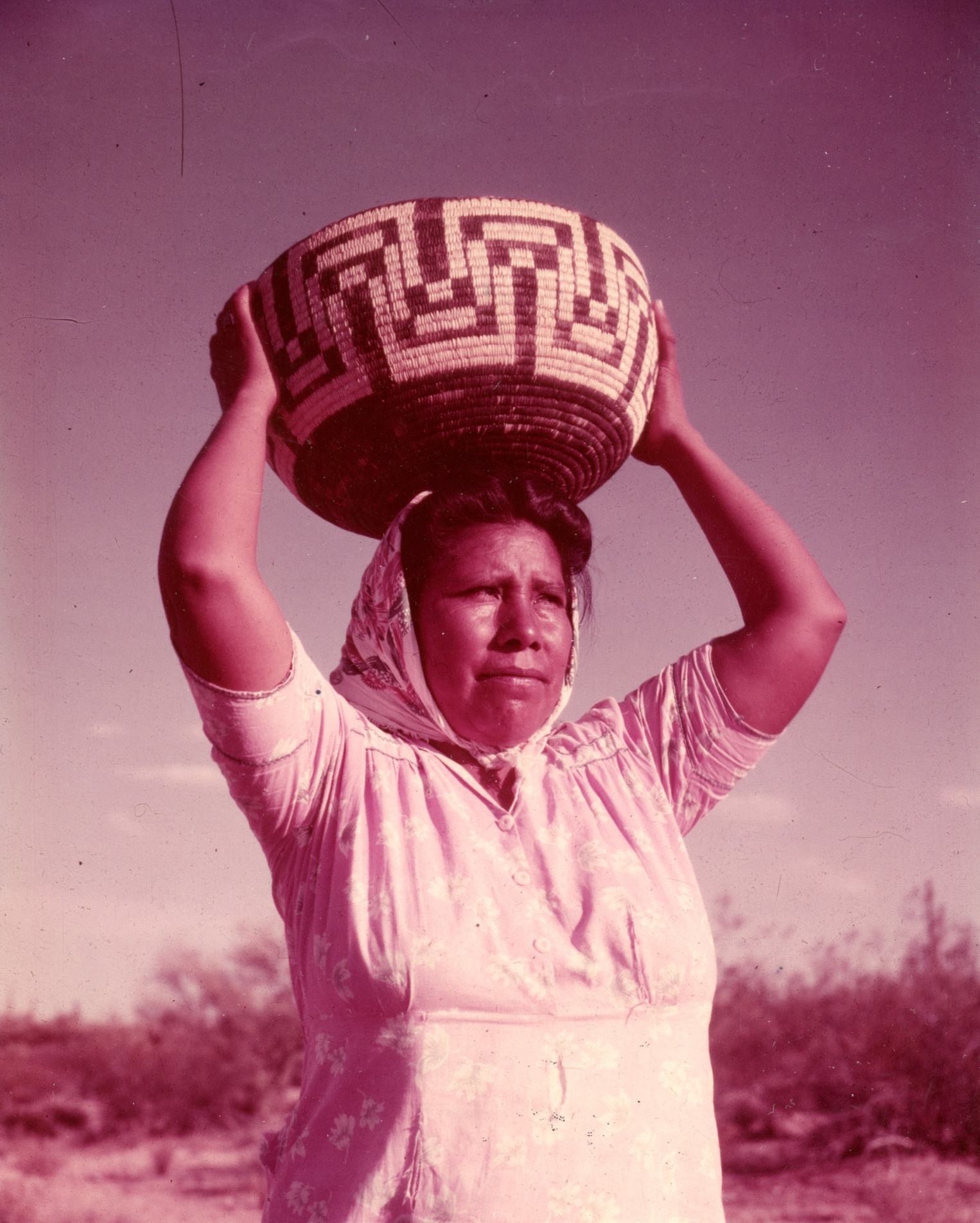 Tohono O'odham woman with a woven basket on her head.