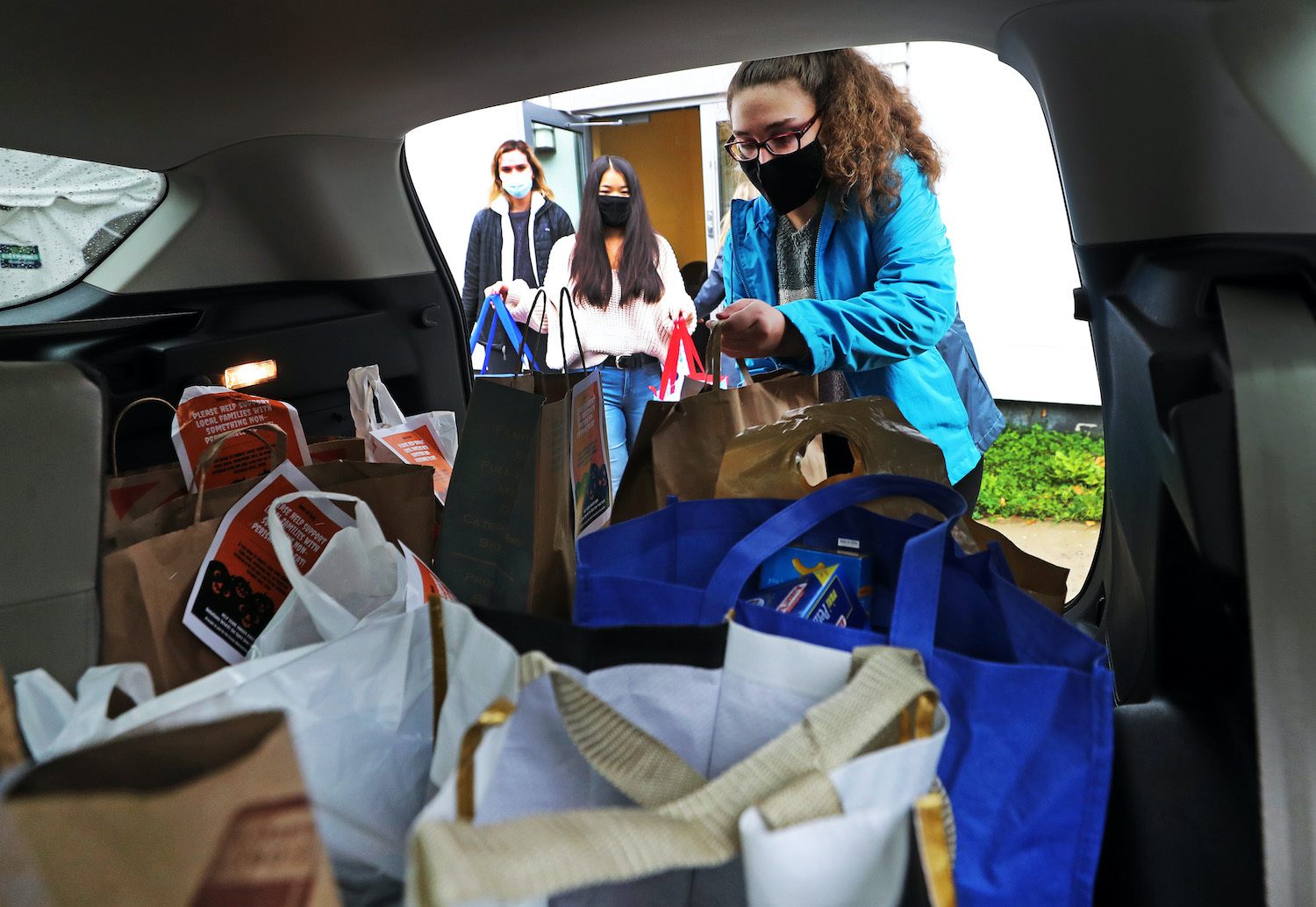 Endicott College student Grace Vartanian, right, and other students load donated food that they have collected into the back of a car for transport in Beverly, MA on Oct. 29, 2020. September 2021